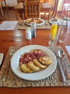a plate of pancakes and bacon on a table at Berg en Zee Guesthouse in Gordonʼs Bay