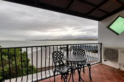 a balcony with a table and chairs and the ocean at Berg en Zee Guesthouse in Gordonʼs Bay