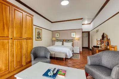 a bedroom with a bed and two chairs and a table at Berg en Zee Guesthouse in Gordonʼs Bay