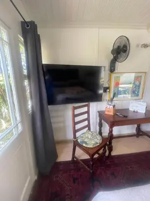 a room with a chair and a table and a television at Waterberry Hideaway in Pringle Bay