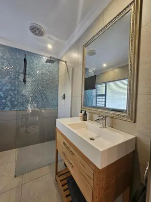 a bathroom with a sink and a mirror and a shower at Induli on Sage in Plattekloof