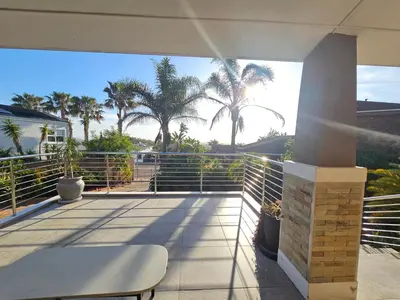 a balcony with a table and palm trees on the beach at Induli on Sage in Plattekloof