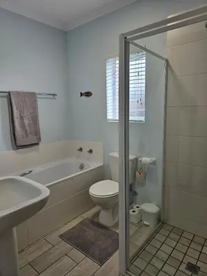 a bathroom with a tub and a toilet and a sink at Torbrae Cottage in Hermanus
