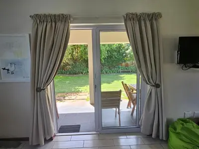 a sliding glass door with a view of a yard at Torbrae Cottage in Hermanus
