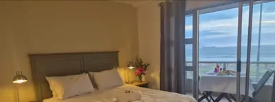 a bedroom with a bed with a view of the ocean at Seaspray Apartment Blauberg in Cape Town