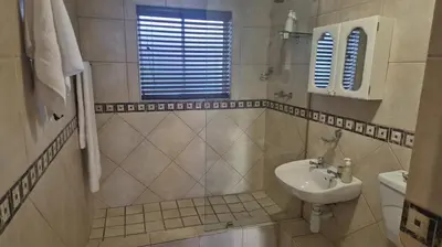 a white bathroom with a sink and a toilet at Seaspray Apartment Blauberg in Cape Town