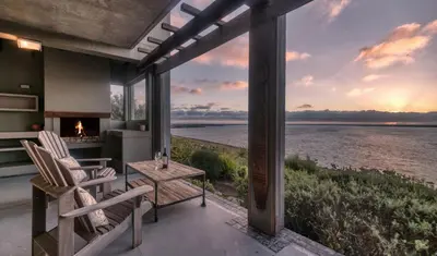 a patio with chairs and a fireplace with a view of the water at Exclusive Estate, Panoramic Beauty, Watersports in Lake Marina