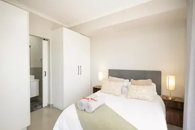 a bedroom with a white bed with towels on it at Durbanville Daydream in Durbanville