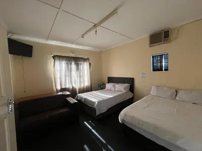a bedroom with two beds and a couch and a window at Heritage lodge in Cape Town