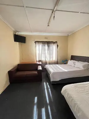 a room with two beds and a couch and a window at Heritage lodge in Cape Town