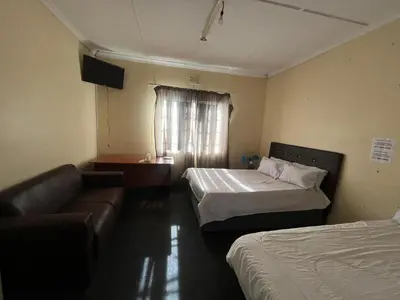 a room with two beds and a couch and a window at Heritage lodge in Cape Town