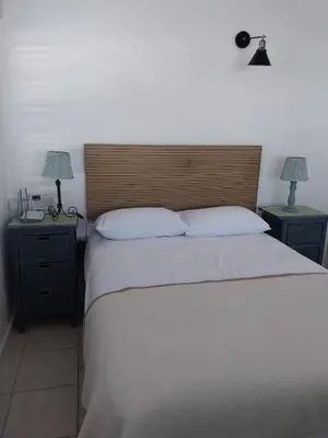 a bedroom with a bed with two nightstands and two lamps at Catch And Release Hermanus in Hermanus