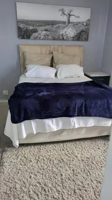 a bed with a blue blanket and pillows on it at Vasco Geusthouse in Goodwood