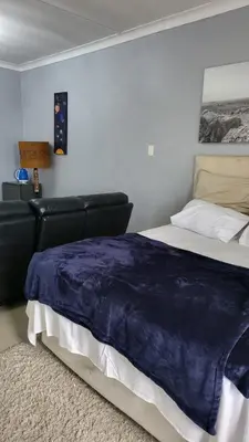 a bedroom with a bed with a blue blanket on it at Vasco Geusthouse in Goodwood