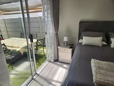 a bedroom with a bed and a table and a window at Home in Somerset Ridge in Somerset West