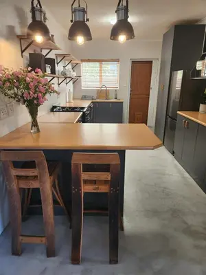 a kitchen with a large wooden table and stools at Home in Somerset Ridge in Somerset West
