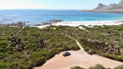 an aerial view of a beach with a car parked on a dirt road at The Sandpiper - The Alikreukel , Pringle Bay in Pringle Bay