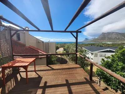 a deck with a bench and a view of mountains at The Sandpiper - The Alikreukel , Pringle Bay in Pringle Bay