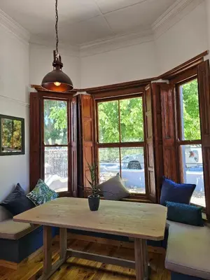 a living room with a table and some windows at Under the Maple in Rawsonville