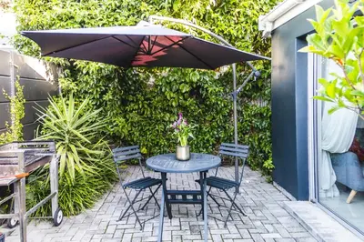 a table and chairs under an umbrella on a patio at Seagull Apartment Hermanus in Hermanus