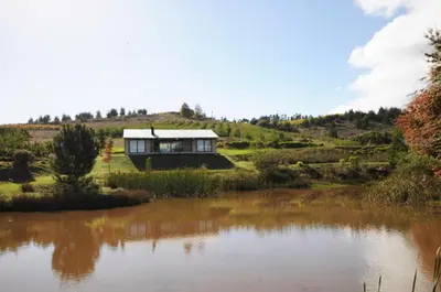 a house on a hill next to a body of water at Galileo Farm in Elgin