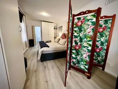 a bedroom with a bed and a mirror at Ebgow Cottage in Cape Town