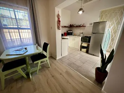 a small kitchen with a table and a refrigerator at Ebgow Cottage in Cape Town