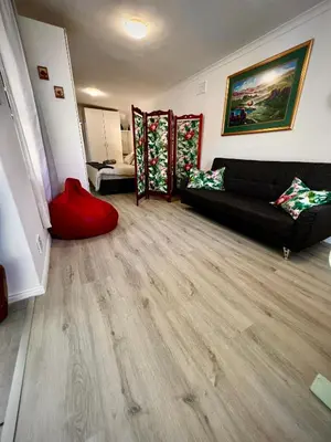 a living room with a black couch and wood floors at Ebgow Cottage in Cape Town