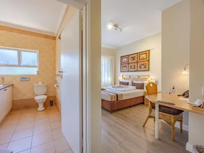 a hotel room with a bed and a bathroom at Hajo's Lodge & Spa in Cape Town