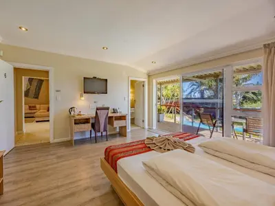 a bedroom with a bed and a desk and a table at Hajo's Lodge & Spa in Cape Town
