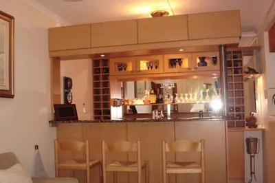 a bar in a living room with wooden chairs at Baleia Guest Lodge in Hermanus