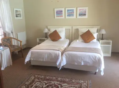 a bedroom with two beds and a chair at Baleia Guest Lodge in Hermanus