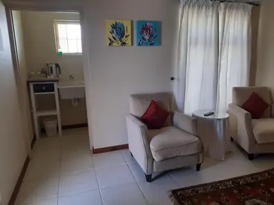 a living room with two chairs and a window at Baleia Guest Lodge in Hermanus