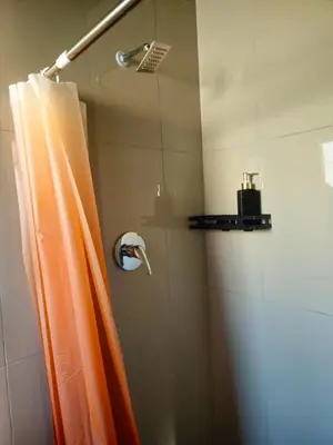 a shower with an orange shower curtain in a bathroom at En suite in Cape Town