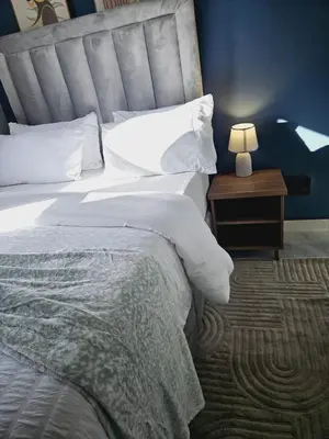 a bedroom with a large bed and a nightstand with a lamp at En suite in Cape Town