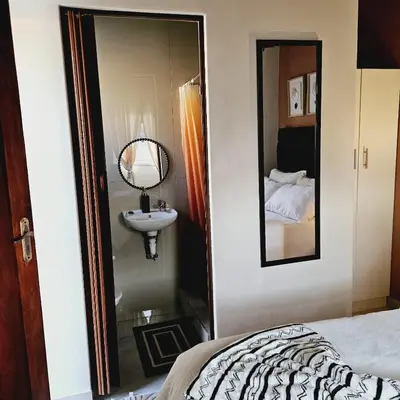 a bedroom with a mirror and a sink and a bed at En suite in Cape Town