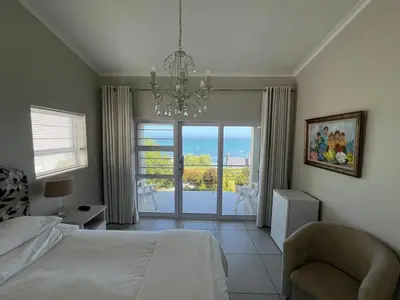 a bedroom with a bed and a chandelier at Vermont Hermanus Flatlet in Hermanus