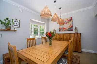 a dining room table with a vase of flowers on it at Sunny Poolside Escape in Somerset West in Somerset West