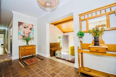 a living room with a staircase and a dresser at Sunny Poolside Escape in Somerset West in Somerset West