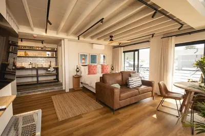a bedroom with a bed and a couch and a table at Oceanfront Duplex Apartments, Hermanus Waterfront in Hermanus