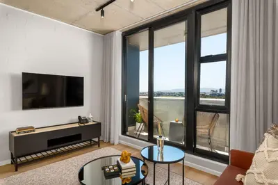 a living room with a tv and large windows at Sunbird Apartments in Cape Town