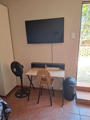 a table with two chairs and a television on a wall at MDA Myburgh in Brackenfell