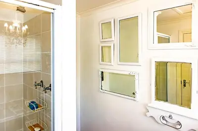 a bathroom with a shower and a sink and a mirror at Upper Dunes Apartment in Pringle Bay