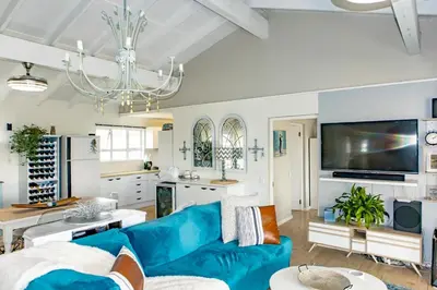 a living room with a blue couch and a kitchen at Upper Dunes Apartment in Pringle Bay