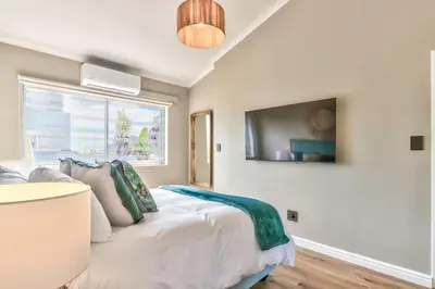 a bedroom with a bed and a tv on the wall at Silverview Modern Duplex Fully Air-Conditioned near Beach in Cape Town