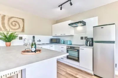 a kitchen with white cabinets and a white refrigerator at Silverview Modern Duplex Fully Air-Conditioned near Beach in Cape Town