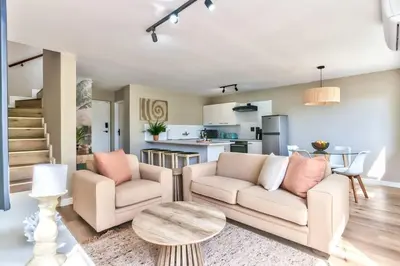 a living room with two chairs and a table at Silverview Modern Duplex Fully Air-Conditioned near Beach in Cape Town