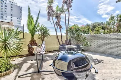 a small boat parked in a courtyard with palm trees at Silverview Modern Duplex Fully Air-Conditioned near Beach in Cape Town