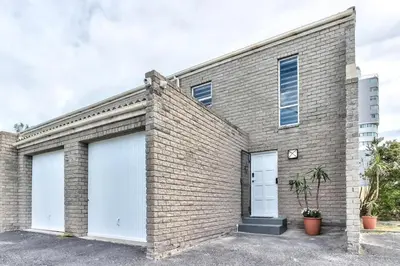a brick house with two white garage doors at Silverview Modern Duplex Fully Air-Conditioned near Beach in Cape Town