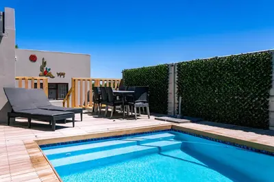 a patio with a table and chairs next to a swimming pool at Onrus Family Retreat in Hermanus